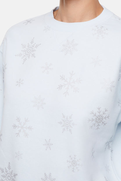 Closeup of light blue sweatshirt with subtle silver snowflake pattern on a white background