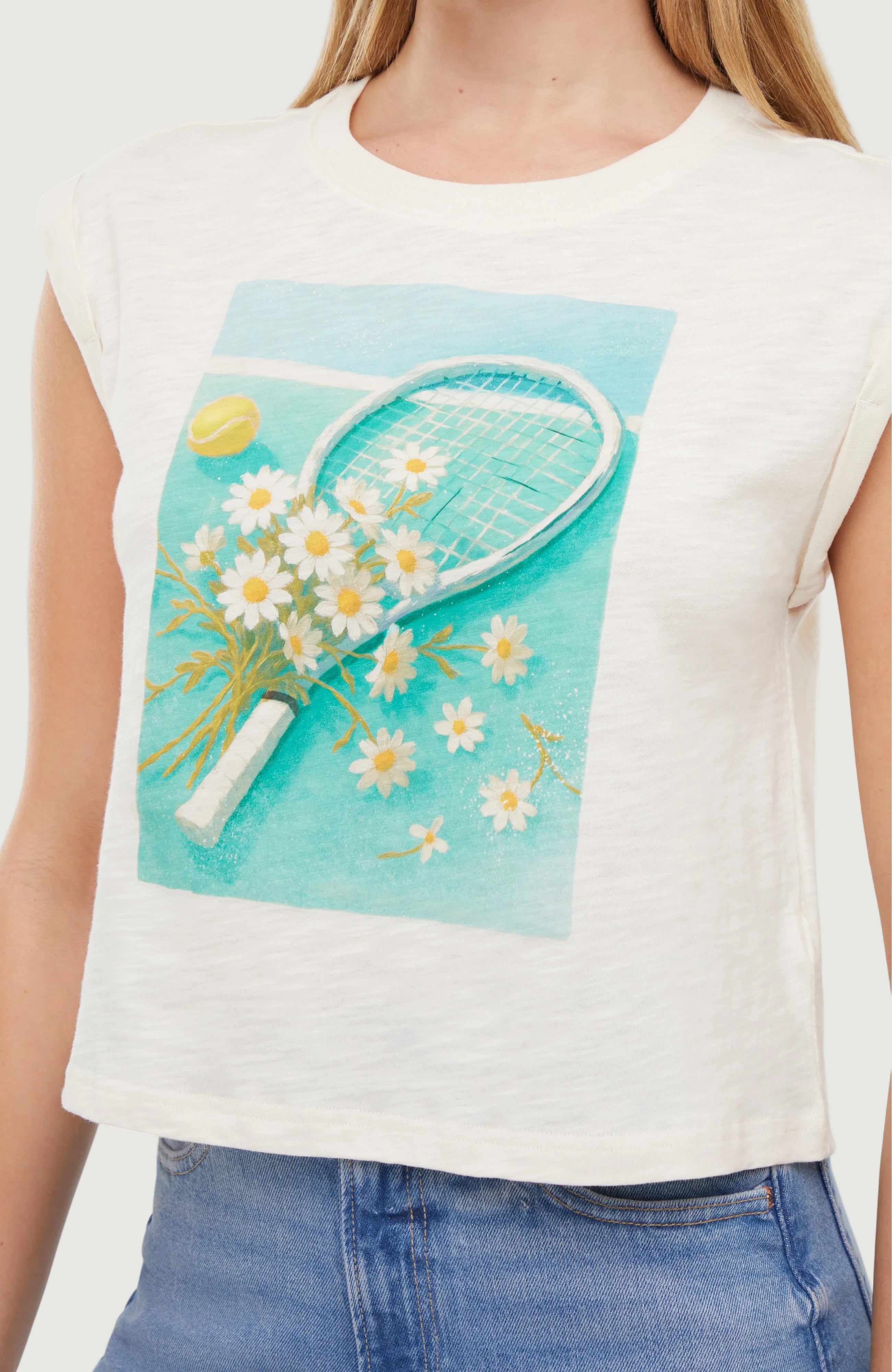 Close up of white sleeveless top with a graphic of a tennis racket and flowers on a turquoise background.