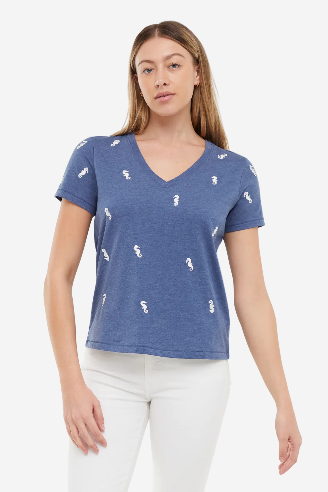 Woman wearing a blue t-shirt with white  embroidered seahorse patterns on a white background