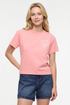 Front view of woman wearing a pale pink/red t-shirt with white &