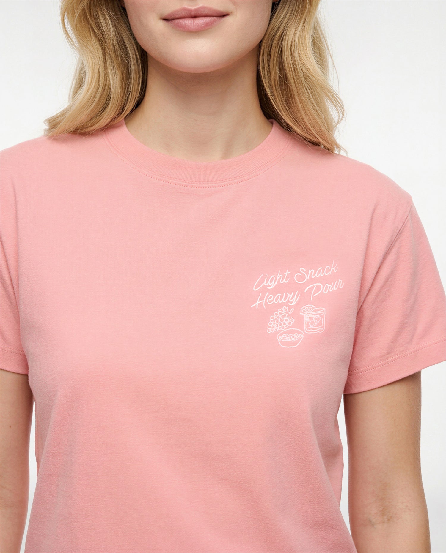 Front view of woman wearing a pale pink/red t-shirt with white &
