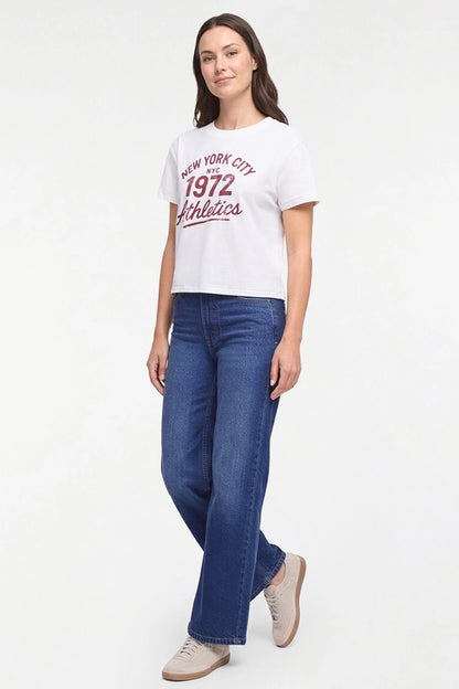 A woman modeling a white short-sleeve graphic T-shirt with red text reading &