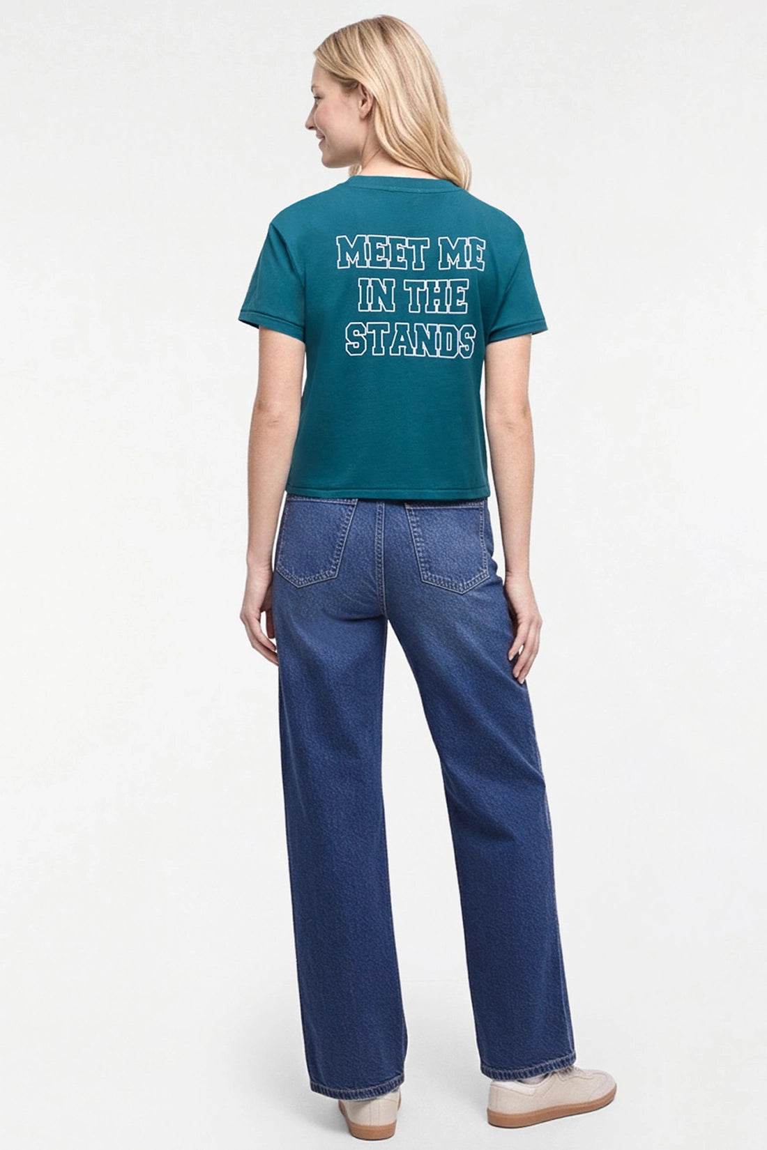 A woman shown from the back wearing a teal cropped t-shirt with &
