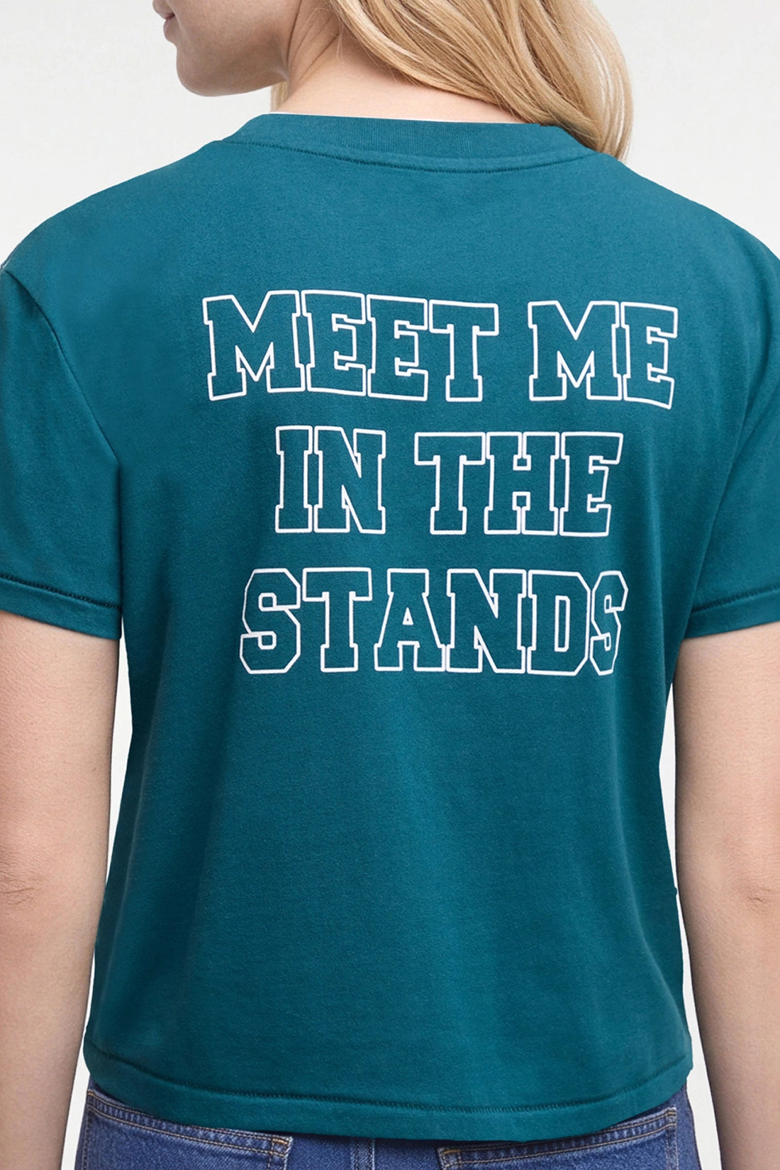 A woman viewed from the back wearing a teal short-sleeve t-shirt with the phrase &