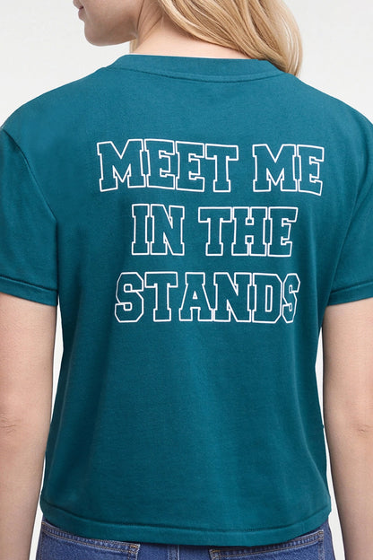 A woman viewed from the back wearing a teal short-sleeve t-shirt with the phrase &