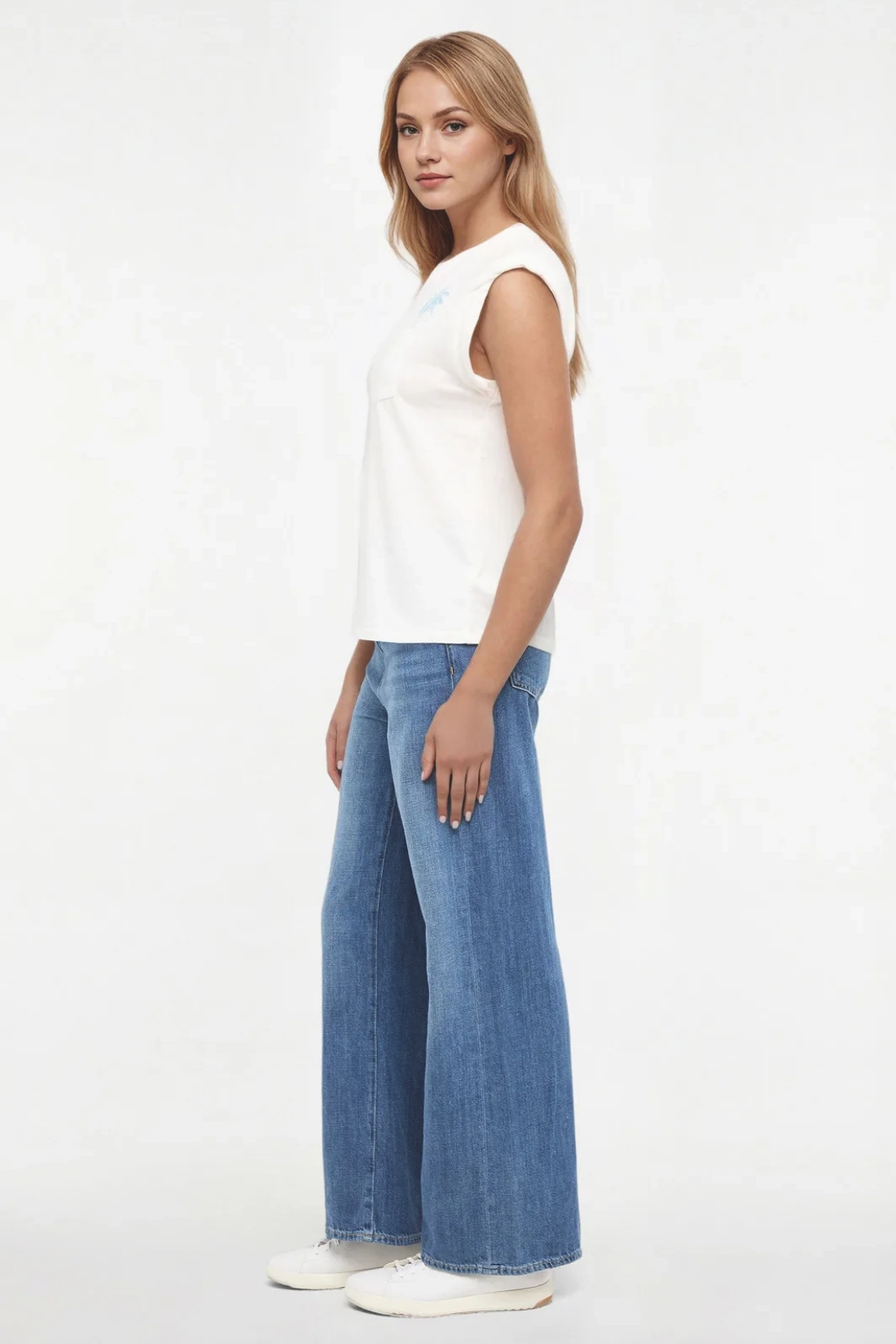 Side view of woman wearing a white t-shirt with "LAS PALMAS BEACH CLUB; GRAN CANARIA, ESPANA" text and graphic design featuring two palm trees and blue jeans on a white background. 