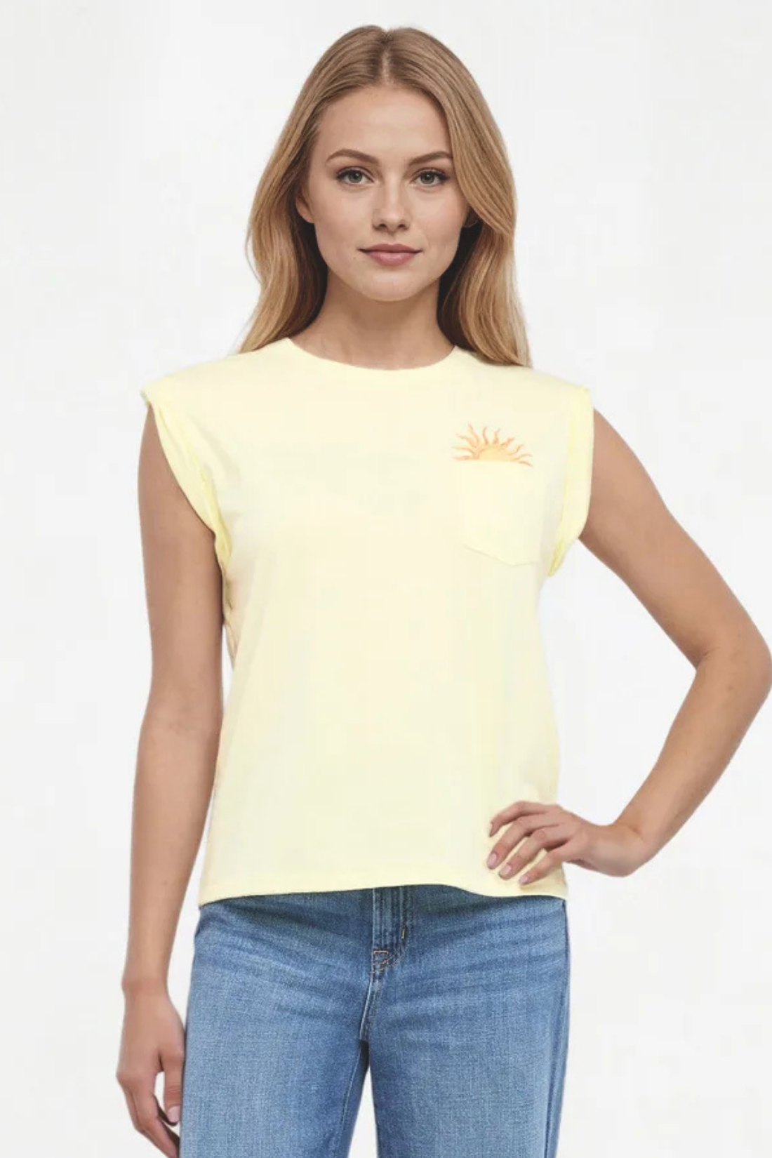 Front view of woman wearing light yellow t-shirt with sun graphic design and blue jeans on a white background. 
