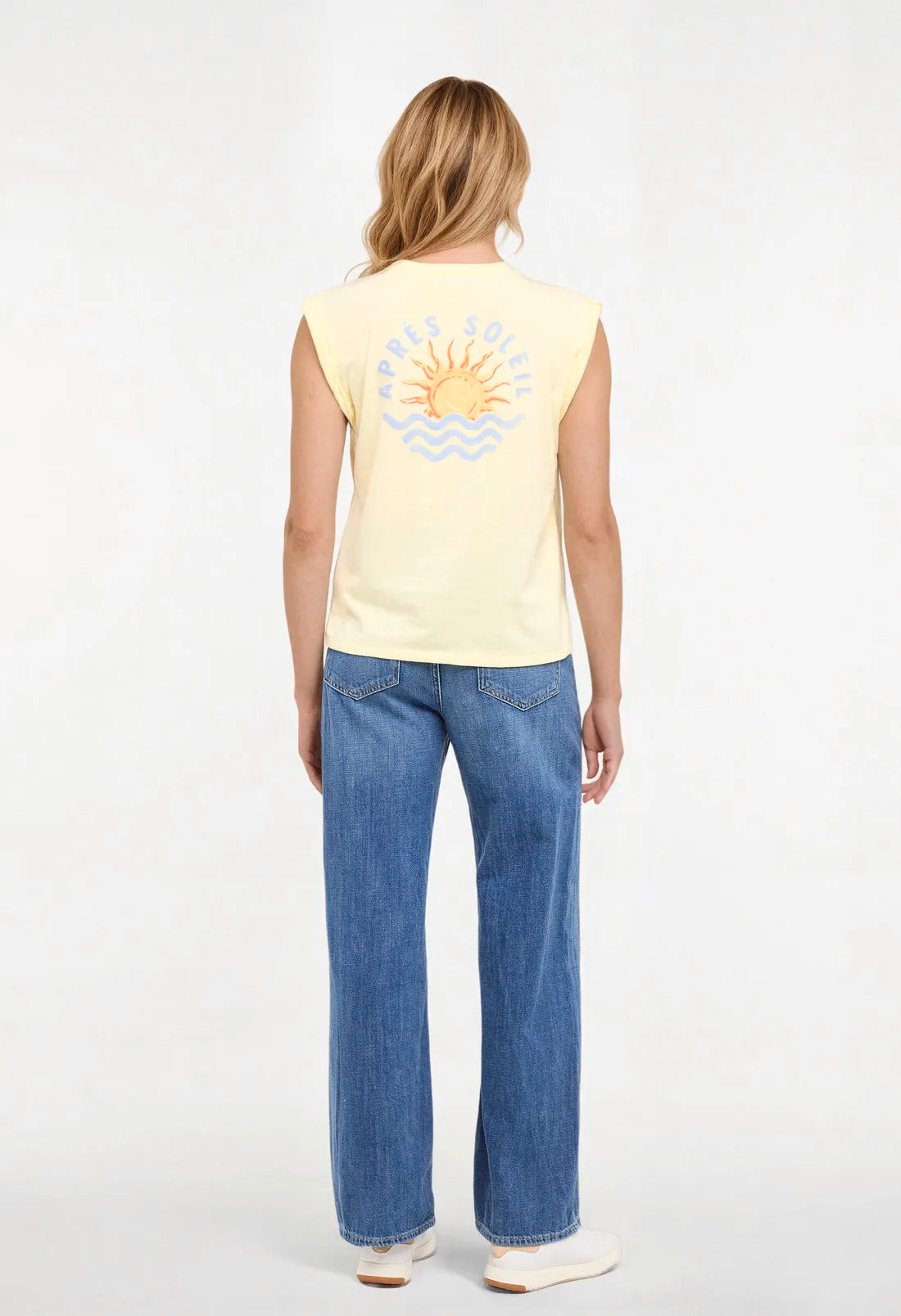 Back view of woman wearing a yellow sleeveless shirt with a sun and wave design and &