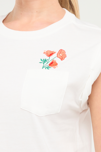 Close up front view of woman wearing white t-shirt with floral embroidery graphic design on top left chest pocket and blue jeans on a white background. 