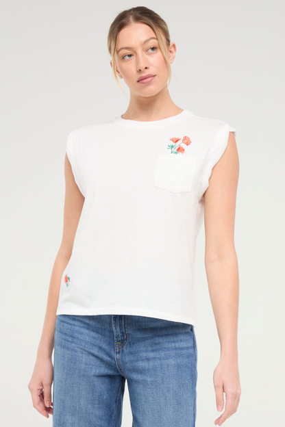 Front view of woman wearing white t-shirt with floral embroidery graphic design on top left chest pocket and blue jeans on a white background. 