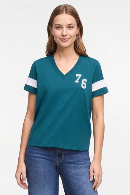 A woman modeling a teal short-sleeve V-neck t-shirt with white stripes on the sleeves and the number &