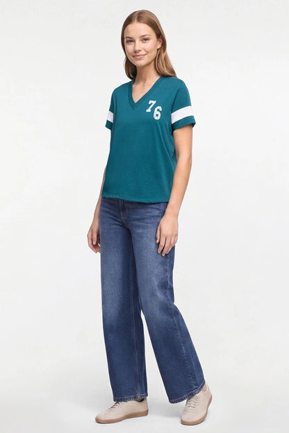 A woman modeling a teal short-sleeve V-neck t-shirt with white stripes on the sleeves and the number &