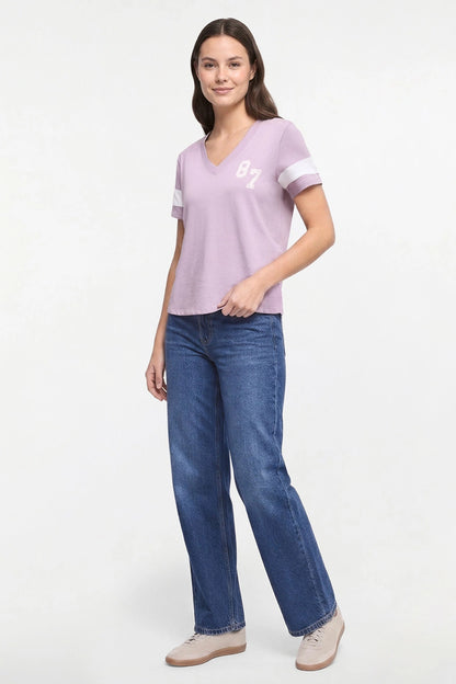 A woman modeling a light purple v-neck t-shirt with white sleeve stripes and &