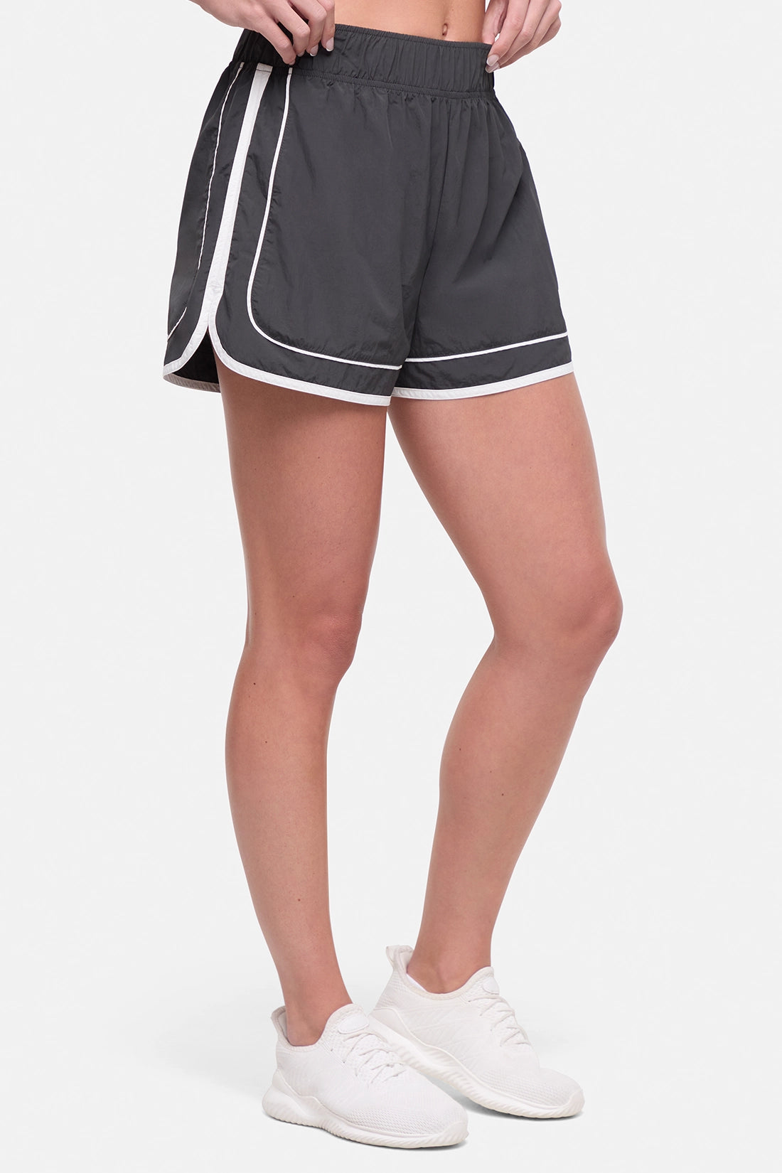 Front view of dark gray athletic shorts with white trim worn by a woman on a white background. 