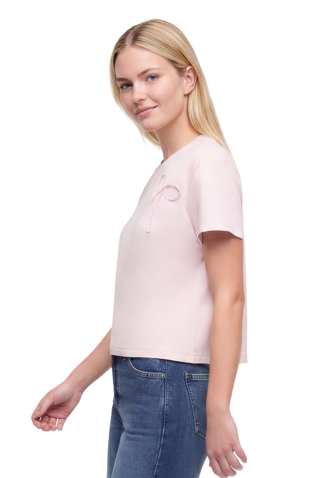 Side view of woman wearing a light pink t-shirt with a bow fabric design and blue jeans on a white background. 