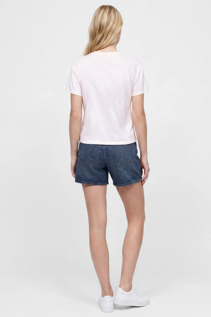 Back view of woman wearing a white t-shirt and jean shorts on a white background. 
