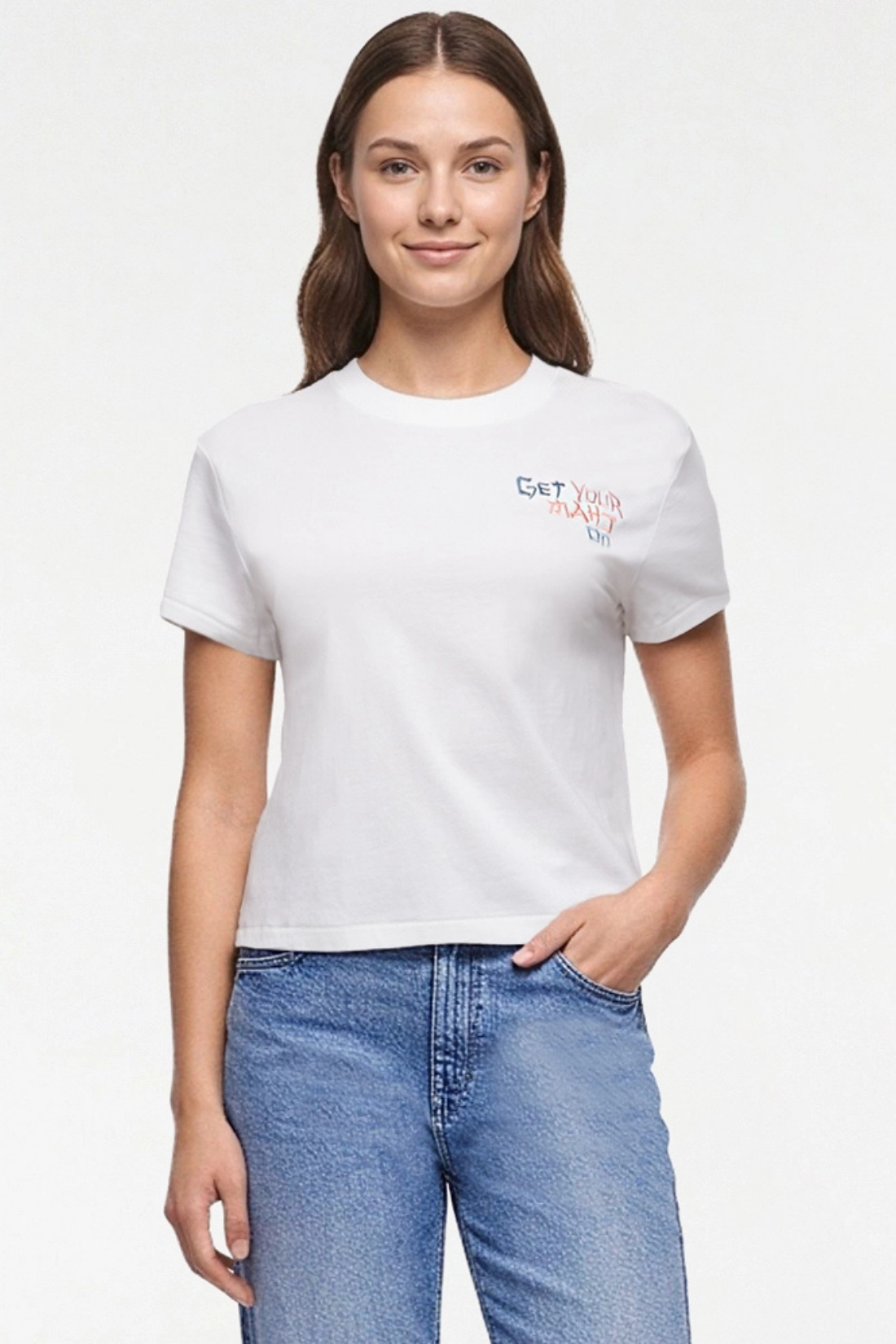 A woman modeling a white short-sleeve crewneck t-shirt with a small colorful graphic on the left chest that reads &