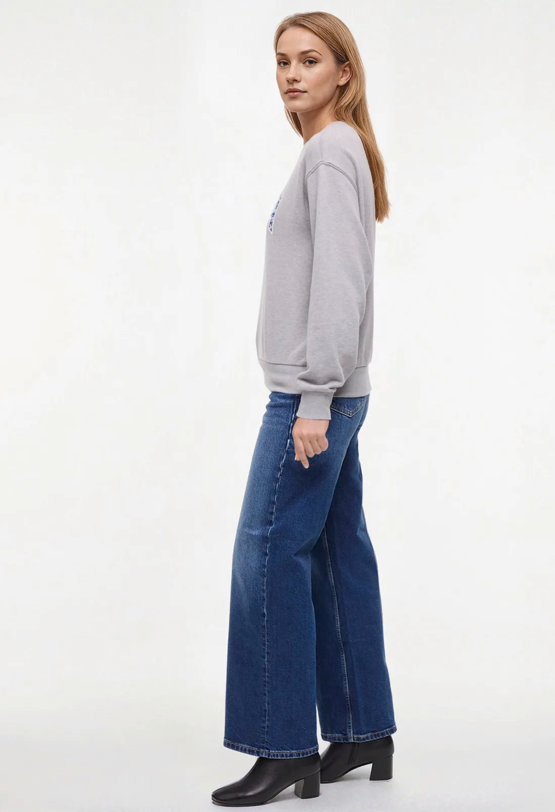 Side view of woman wearing a heather gray sweatshirt with &