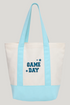 A canvas tote bag with a cream body, light blue handles and bottom panel, and &