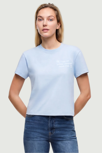 Front view of woman wearing a light blue t-shirt with embroidered &