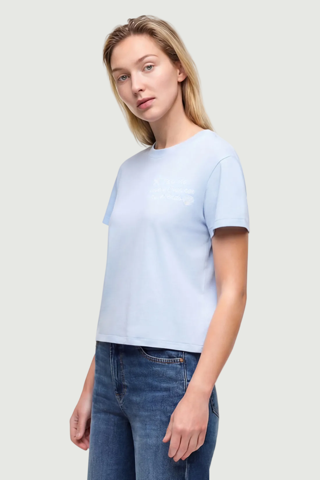 Side view of a woman wearing light blue t-shirt with embroidered &