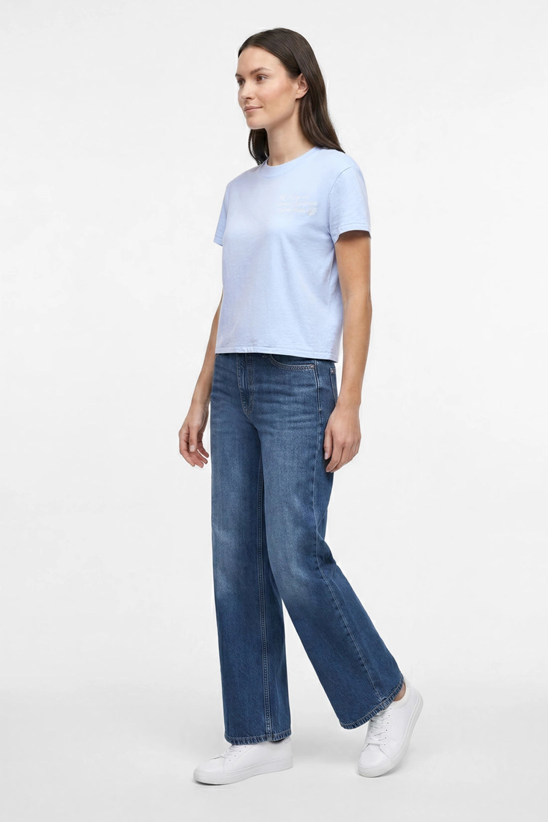 Side view of a woman wearing light blue t-shirt with embroidered &