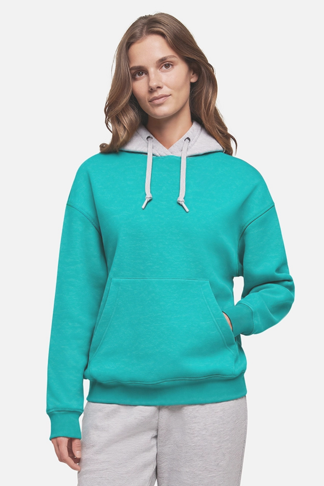 A woman wearing a turquoise teal pullover hoodie with a light gray inner hood lining and white drawstrings, paired with light gray sweatpants, against a plain light gray background. 