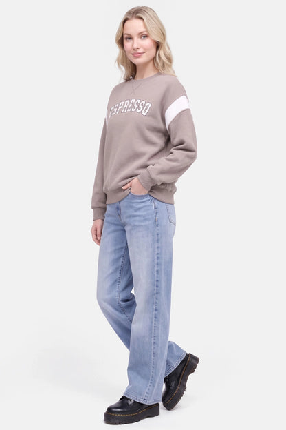 A woman modeling a taupe crewneck sweatshirt with white &