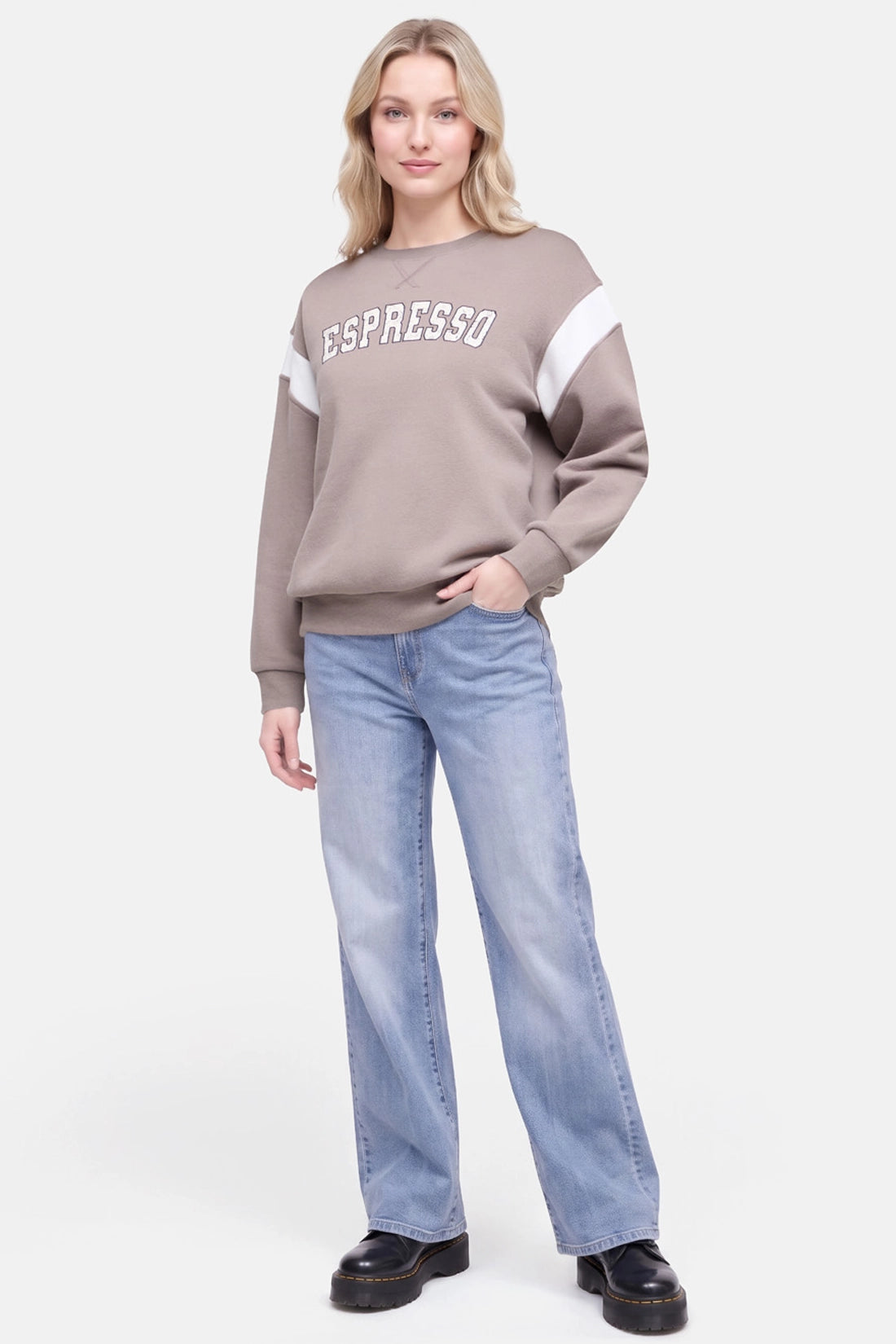 A woman modeling a taupe crewneck sweatshirt with white sleeve stripes and &