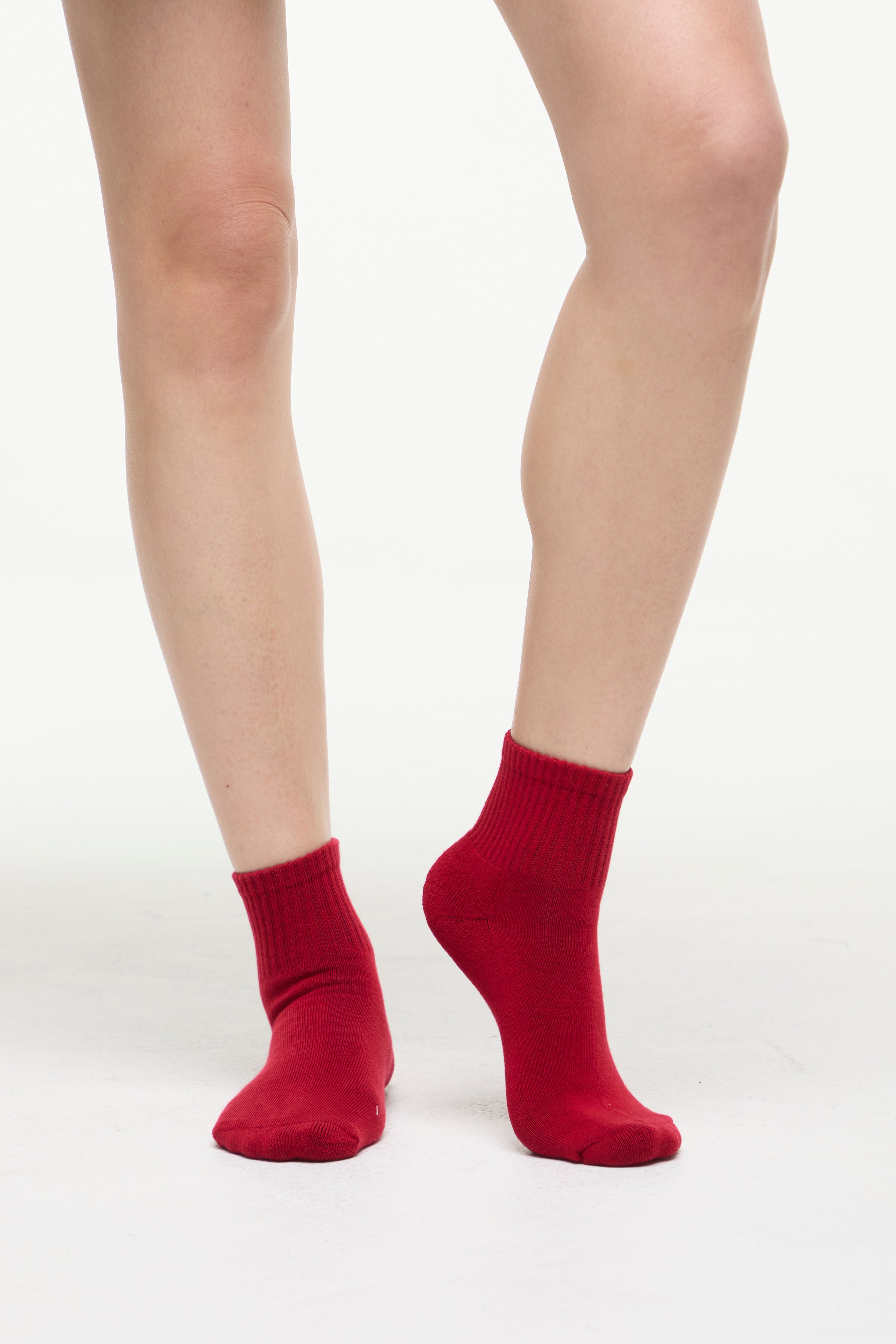 Red socks worn by a woman on a white background. 