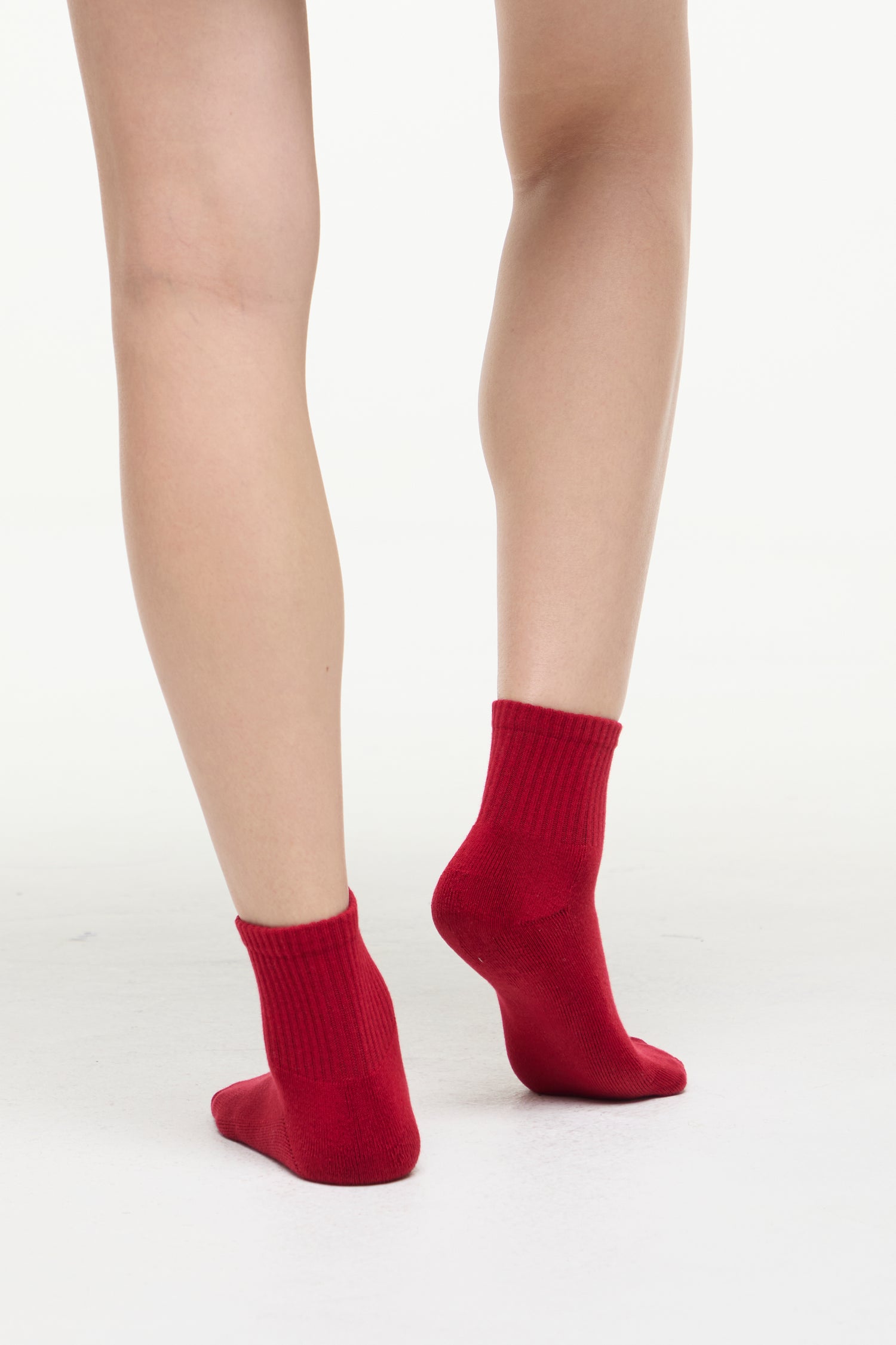 Red socks worn by a woman on a white background. 