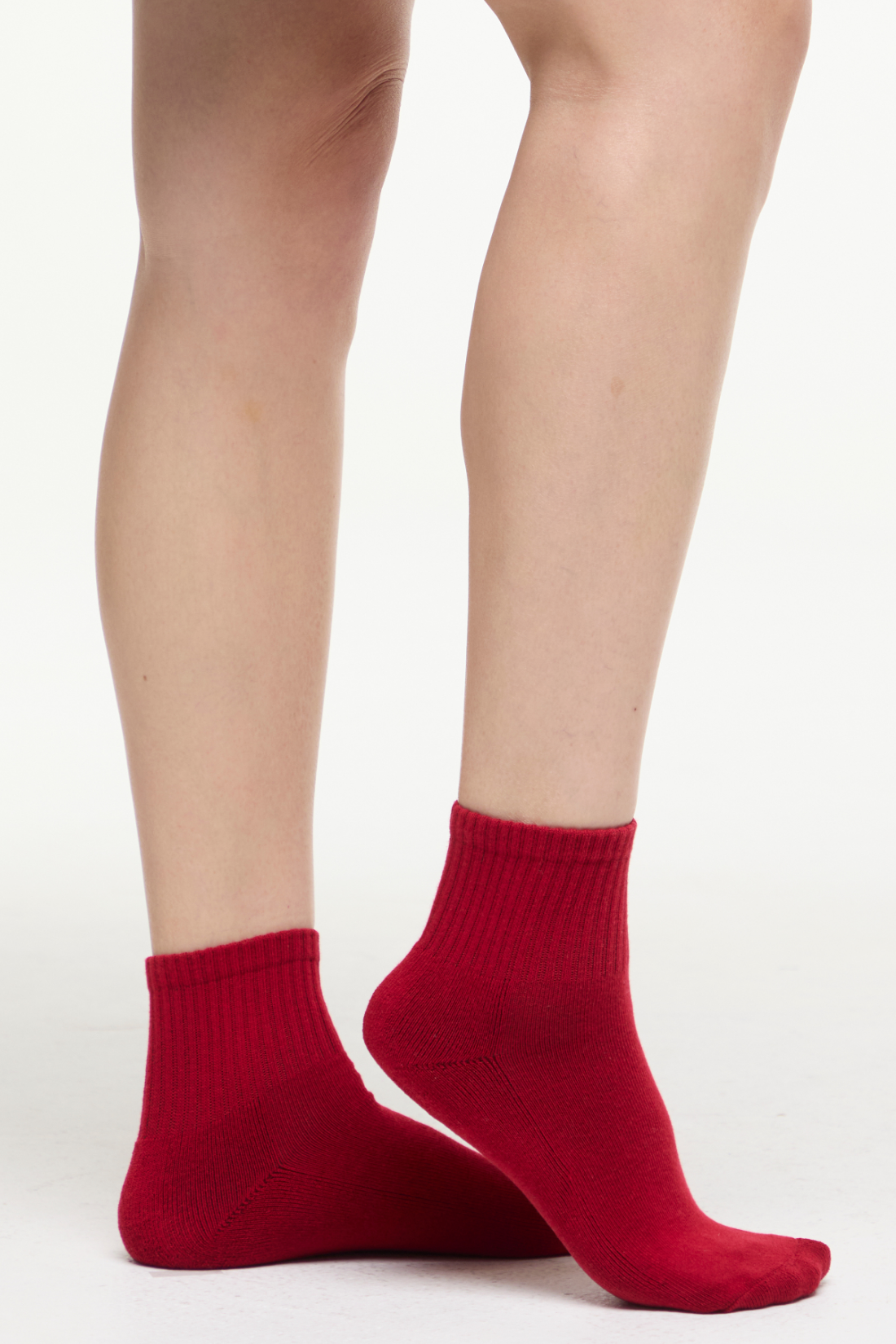 Red socks worn by a woman on a white background. 