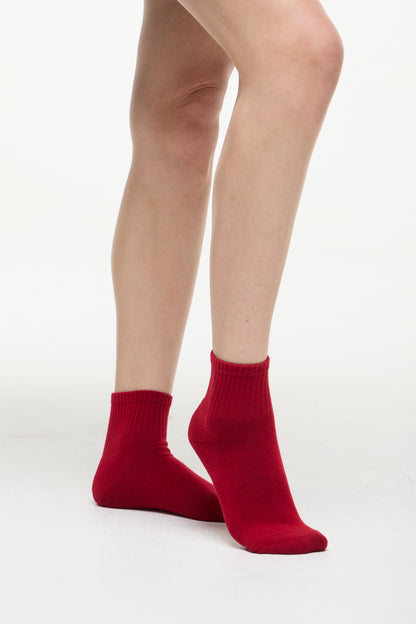 Red socks worn by a woman on a white background. 