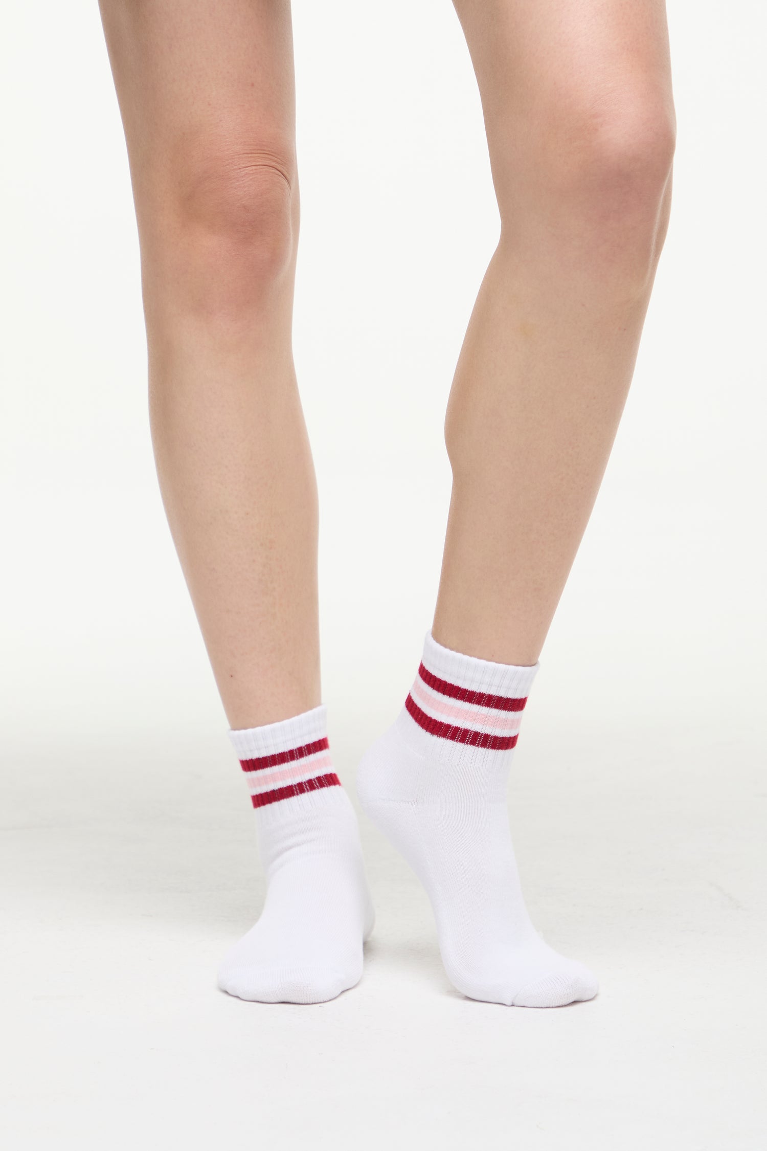 White socks with red/pink stripes worn by a woman on a white background. 