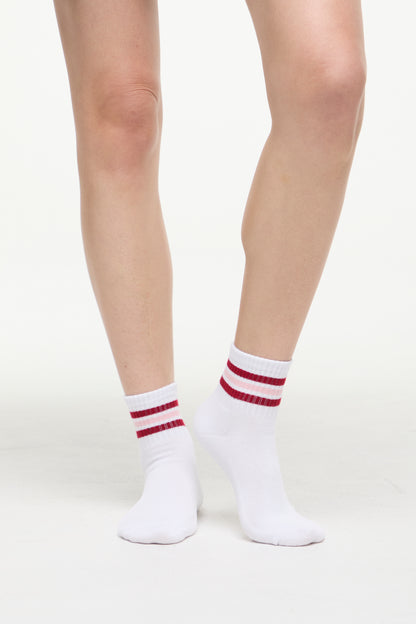 White socks with red/pink stripes worn by a woman on a white background. 
