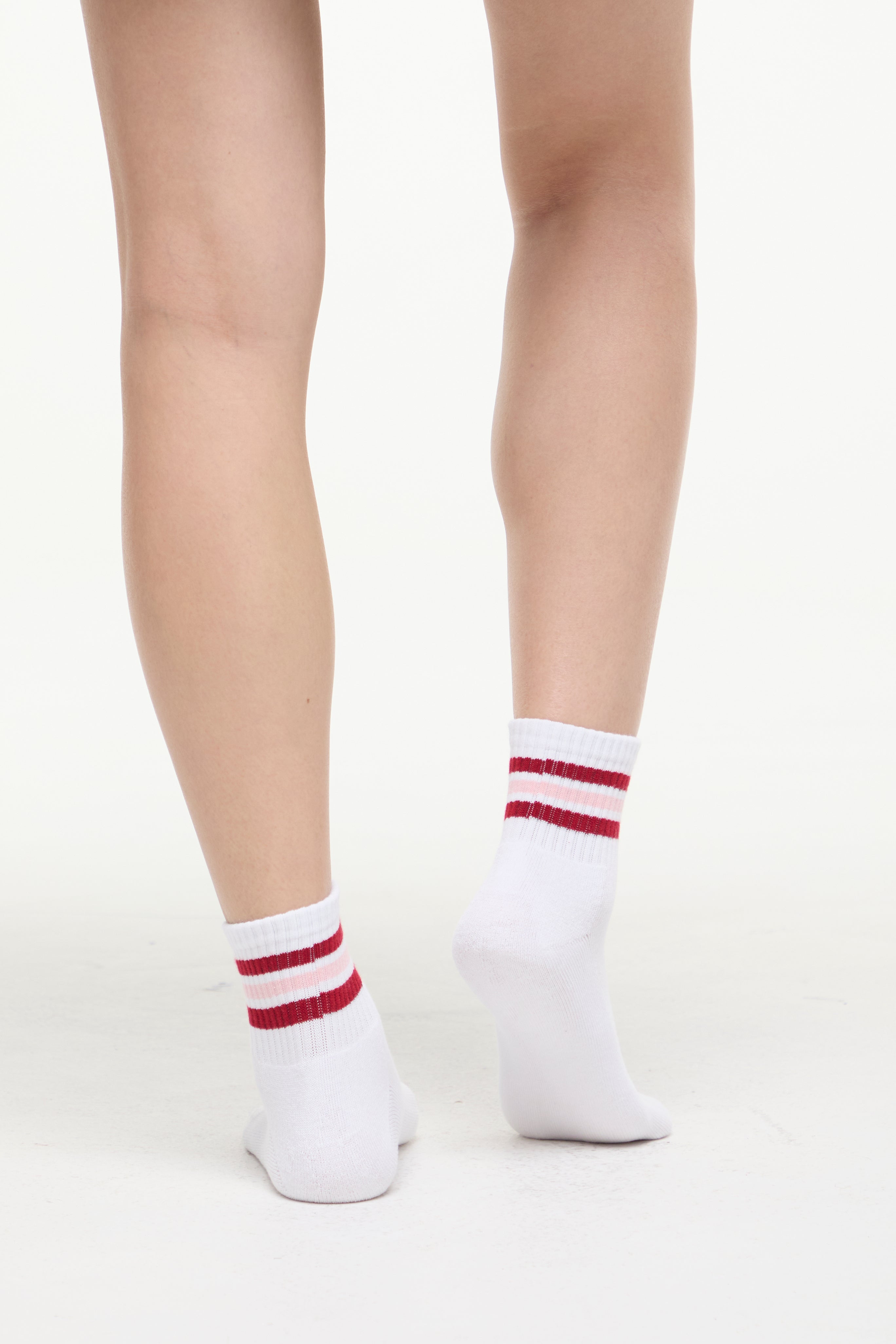 White socks with red/pink stripes worn by a woman on a white background. 