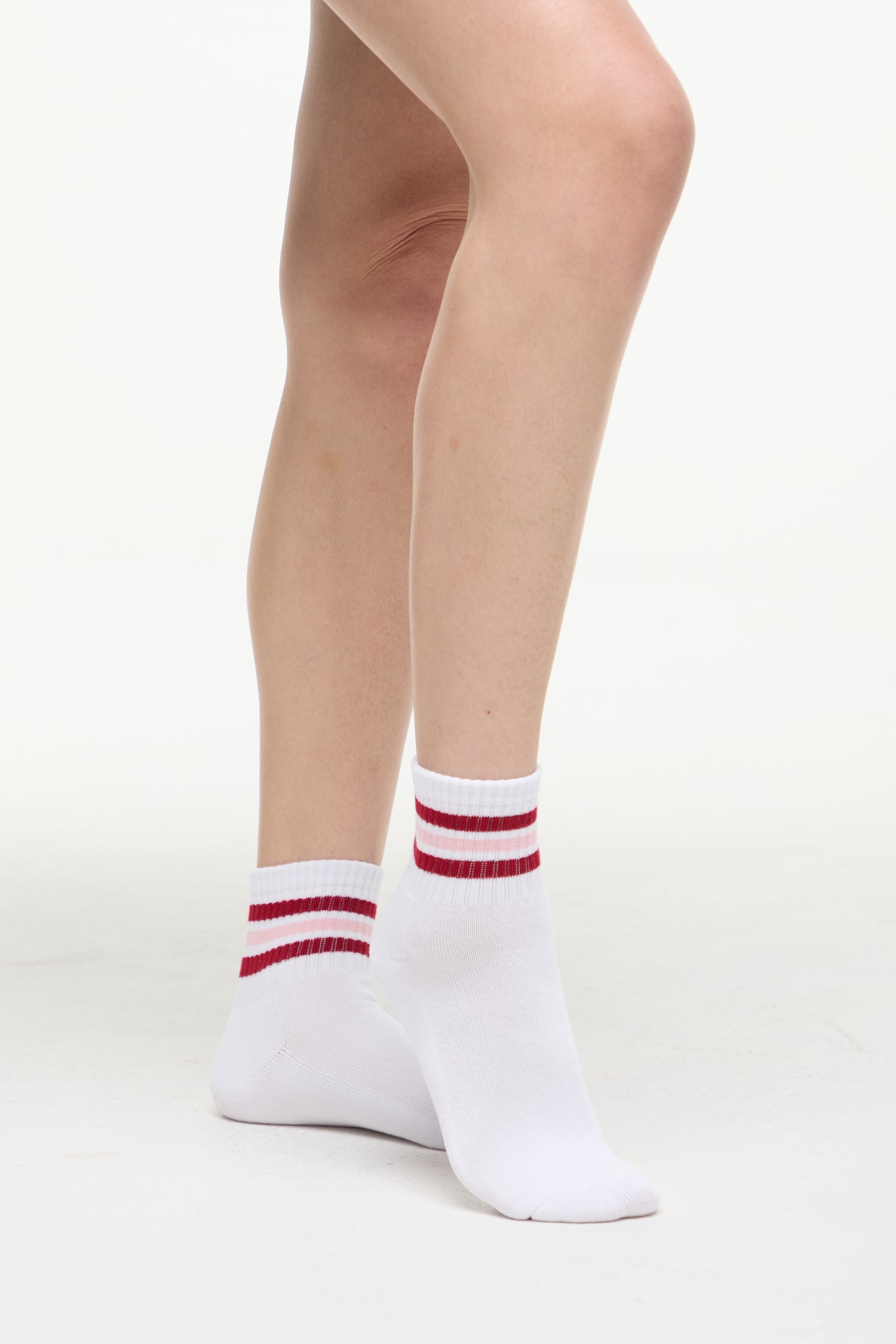 White socks with red/pink stripes worn by a woman on a white background. 