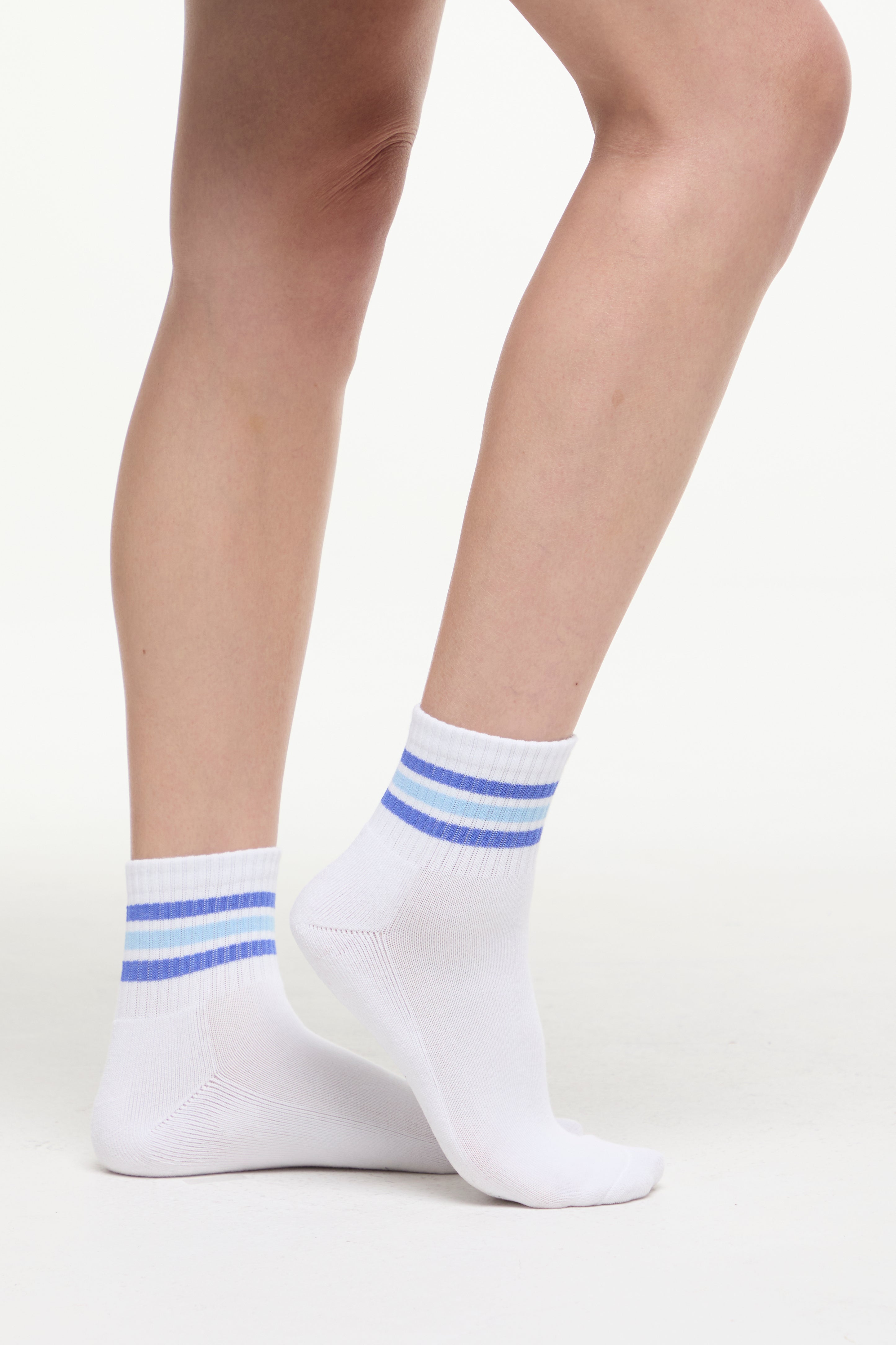 White socks with blue stripes worn by a woman on a white background. 