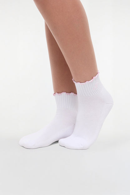 Side view of white socks with lilac ruffled trim and cheer megaphone graphic worn by a woman on a light background. 