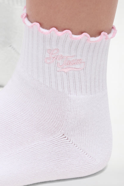 Close up view of white socks with lilac ruffled trim and &