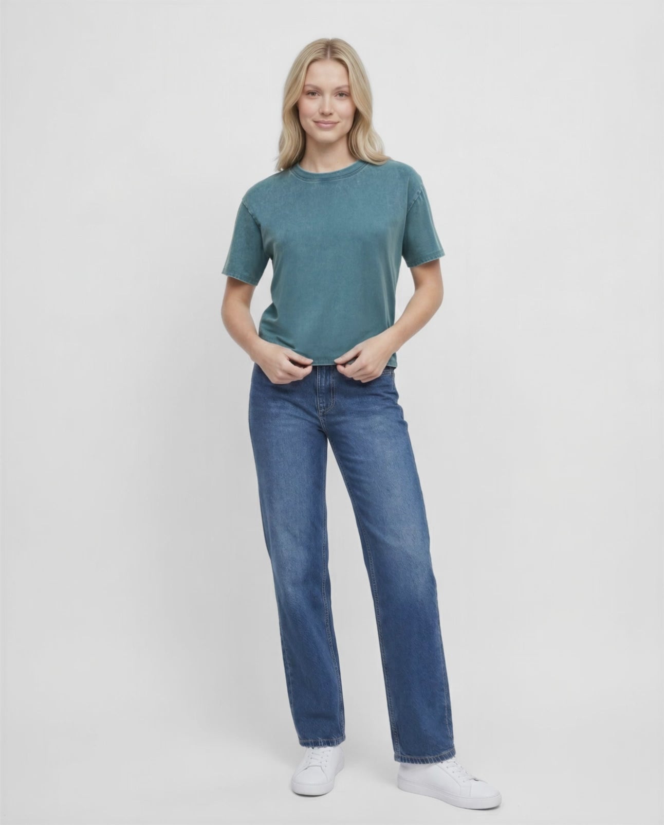 Video view of woman wearing a teal green t-shirt and blue jeans on a white background. #color_deep-teal