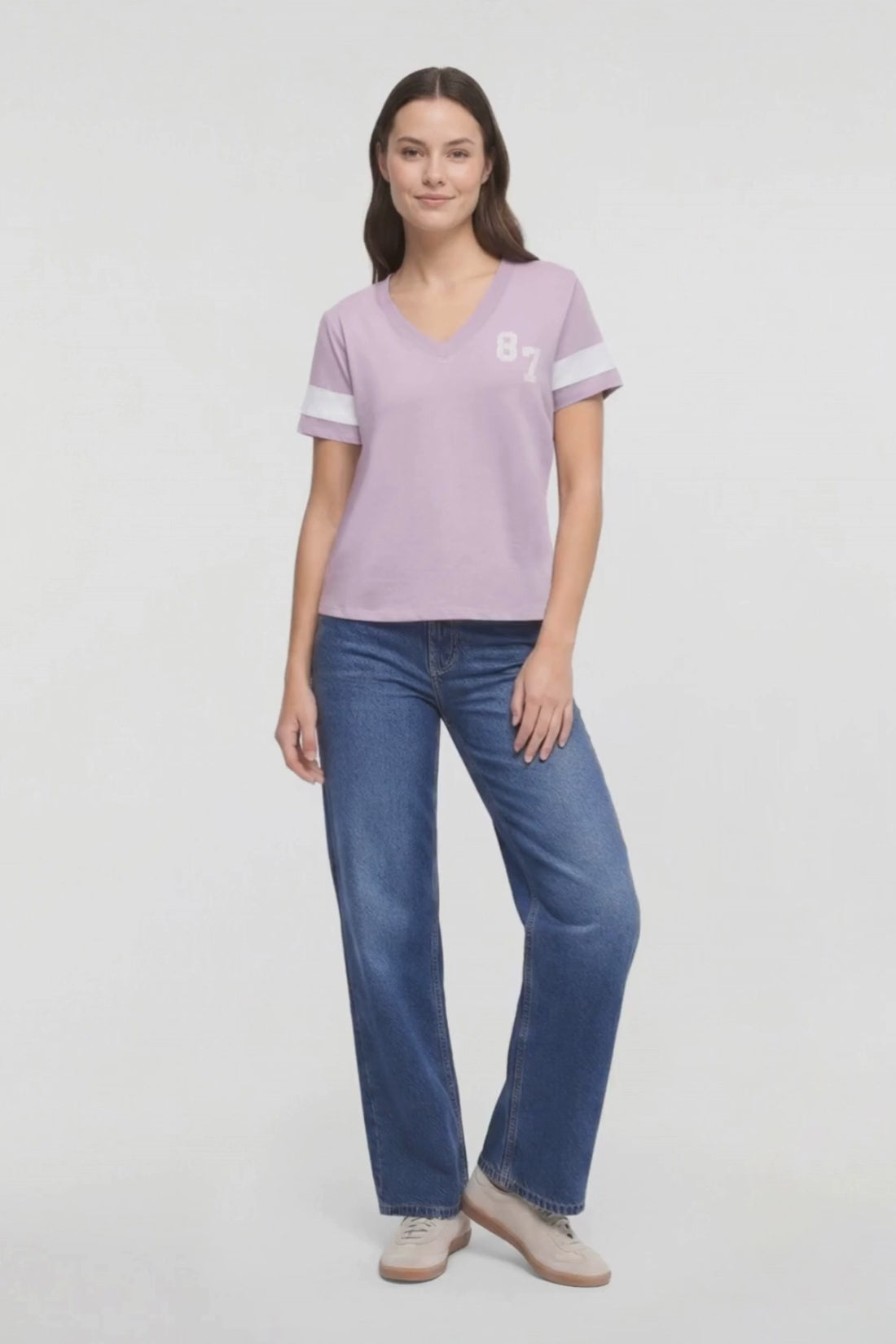 Video of a woman modeling a light purple v-neck t-shirt with white sleeve stripes and &