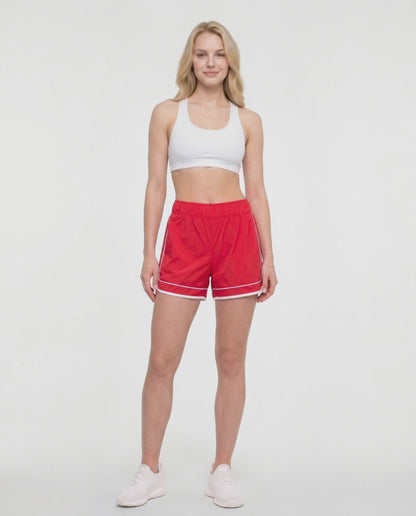 Video view of red athletic shorts with white trim worn by a woman on a white background. 