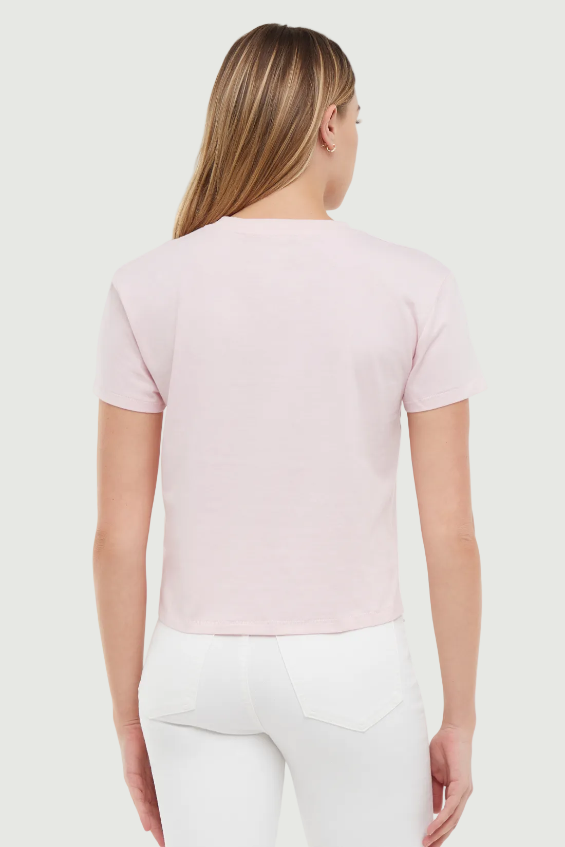 Back view of woman wearing a light pink t-shirt on a white background. 